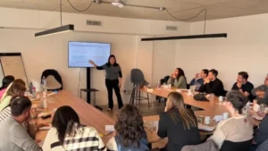 Daniella Rojas presentando un reporte de experiencia durante TAPIA Buenos Aires, con la audiencia tomando notas.